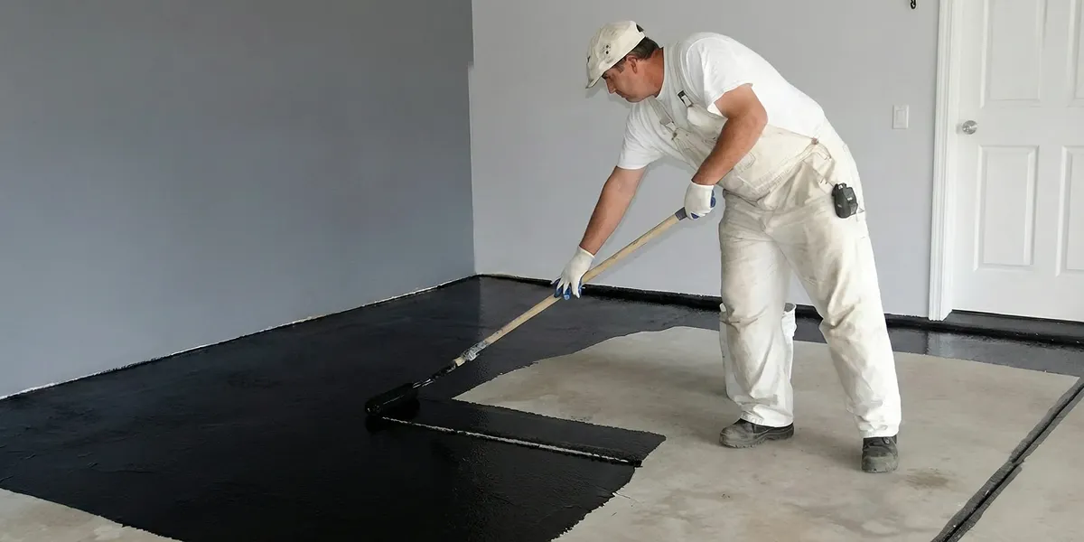 basement waterproofing professional applying waterproof coating to protect a basement floor in Bellevue, WA