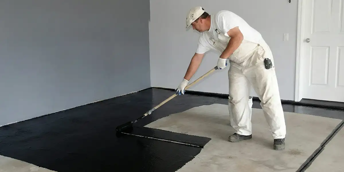 basement waterproofing professional applying waterproof coating to protect a basement floor in Bellevue, WA